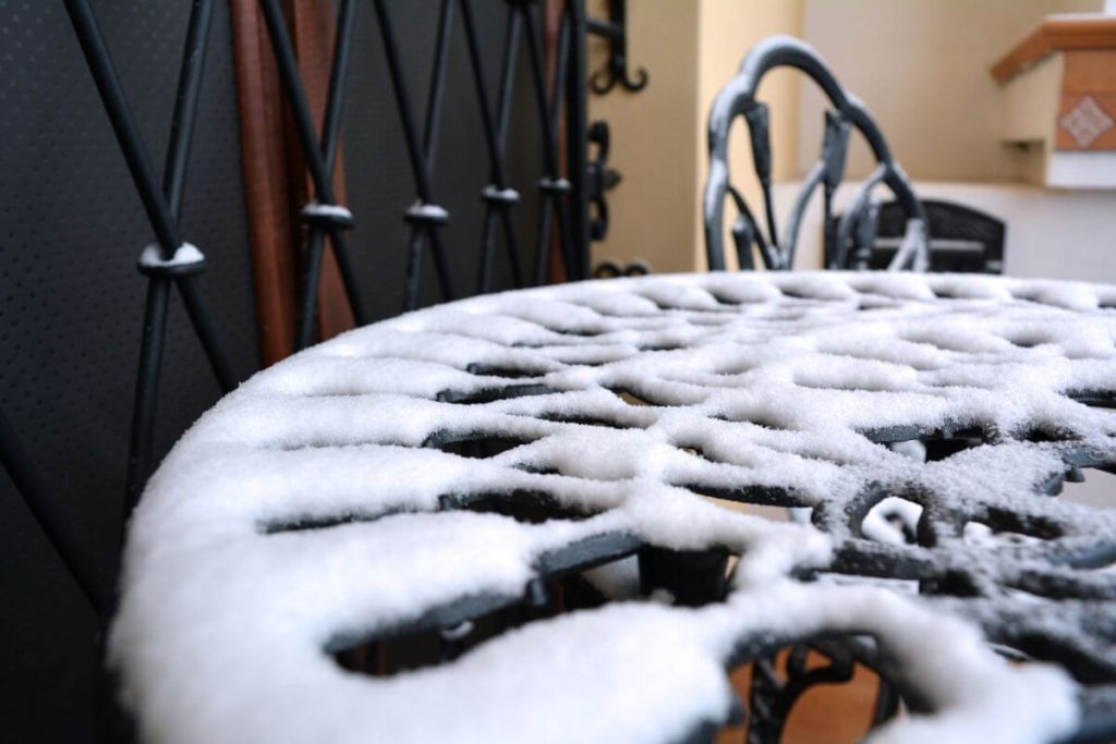 kovový záhradný stolík pokrytý snehom